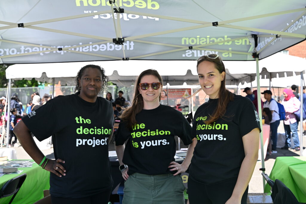 Three volunteers wearing The Decision Project T-shirts at an Infinite Legacy block party to help spread organ, eye and tissue donation awareness in Maryland, Washington, DC and Northern Virginia.