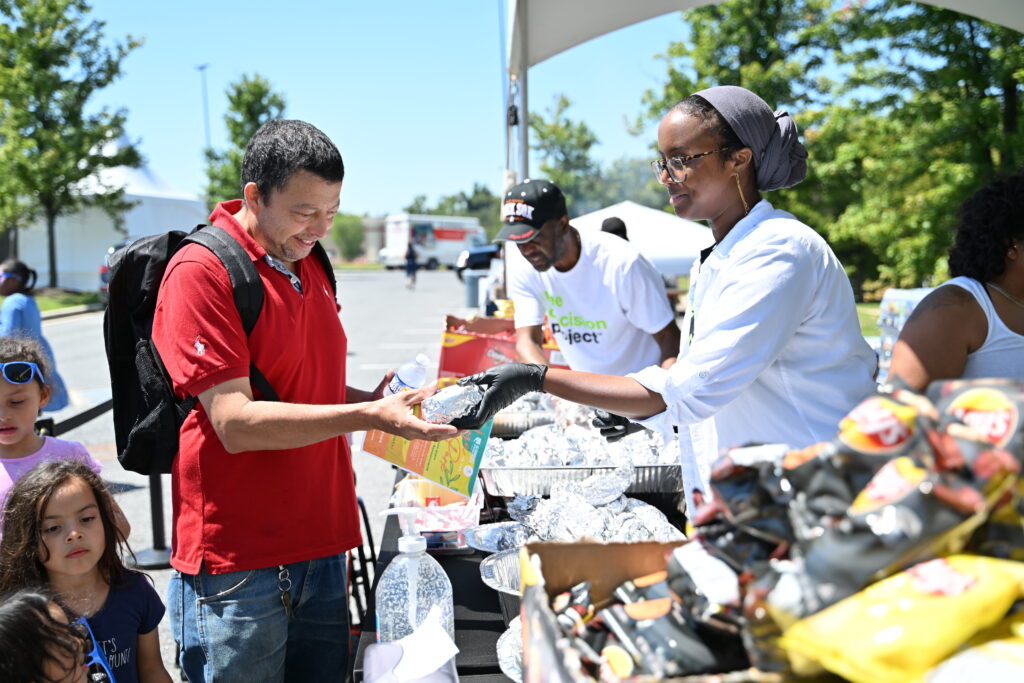 Community outreach team members pass out food at a block party to spread awareness about organ, eye and tissue donation.