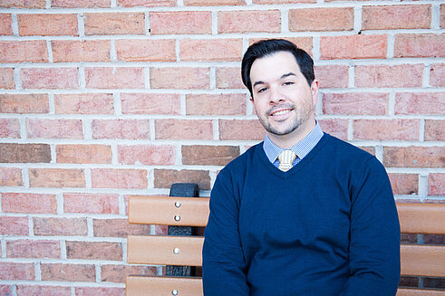 Director, Processing and Operational Logistics, Gary Holmes, sits on a bench outside of Infinite Legacy's office smiling.